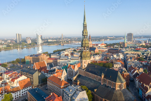 Fototapeta na szkło Aerial view photo from flying drone panoramic to St. Peter's Church and the Old Town on the background of the Daugava River and downtown on a beautiful early morning sunrise (series)