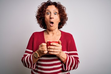 Sticker - Middle age curly hair woman drinking mug of coffee over isolated white background scared in shock with a surprise face, afraid and excited with fear expression