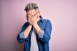 © Krakenimages.com - Young handsome modern man wearing glasses and denim jacket over pink isolated background with sad expression covering face with hands while crying. Depression concept.
