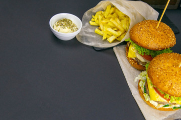 Wall Mural - Two hamburgers close-up, nearby are fries, tomatoes, sauces, tomatoes and peppers. Grill rack in the background