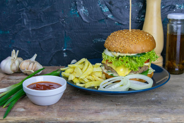 Wall Mural - Close-up hamburger on a blue plate, next to chopped onions, french fries and ketchup