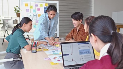 Young Asian business creative team work together, mobile application software design project. Brainstorm meeting, internet technology, office coworker teamwork concept. 4K tilt down forward dolly shot