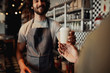 © StratfordProductions - Waiter serving a cup of cold coffee to customer at counter in cafe