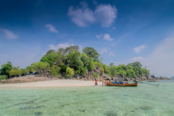 Sev view of long-tail boat floating seaside of green island with blue sky background, Ko Rokroy island, Tarutao Marine National Park, Satun, southern Thailand. a long-tail boat trip from lipe island.