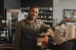 © StratfordProductions - Portrait of young afro-american male business owner behind the counter of a coffee shop smiling looking at camera