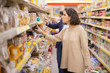 © Mangostar - Serious woman looking at cookies in grocery store. Side view of people choosing baked goods in supermarket, selective focus. Shopping concept
