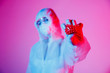 Concept coronavirus protection against epidemics. Young woman in protective suit, medical mask and glasses on pink and blue background
