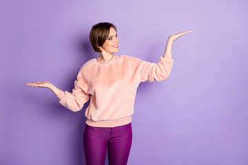 Poster - Portrait of cheerful positive girl hold hand raise palm up compare offer try choose promotion adverts wear pastel pullover isolated over violet color background