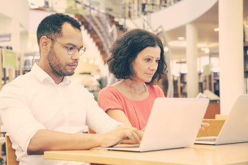 Wall Mural - focused college students working in library computer class. man and woman in casual sitting at desk,