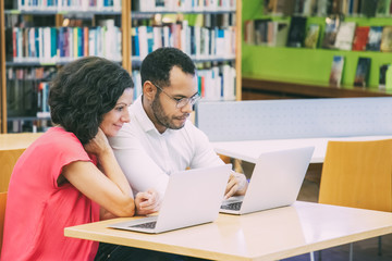 Wall Mural - couple of adult students doing and discussing academic research in library. man and woman in casual 