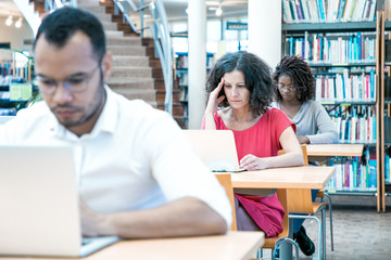Wall Mural - diverse adult students working on computer in classroom. focused sitting at desks and using laptops.