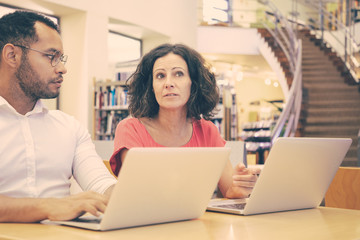 Wall Mural - excited college students discussing research specifics in library. man and woman in casual sitting a