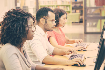 Wall Mural - diverse group of adult students working in computer class. line of man and women in casual sitting a