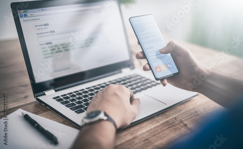 Fotomural Man works at home and uses a smart phone and notebook computer.