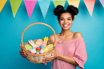 Photo of pretty dark skin lady hold holiday basket came family easter dinner eggs ginger bread bunny hang flags wear red white striped shirt naked shoulders isolated blue color background