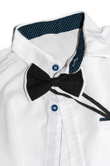 White men's shirt with a black and white bow-tie lies on the table, closeup top view