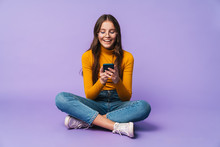 Image Of Young Woman Holding Smartphone While Sitting With Legs Crossed