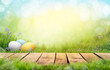 canvas print picture - A wooden product display top with an Easter background of painted eggs and green grass and meadows.