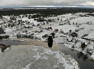 Aerial view from the top  winter day river bend  with snowy frozen shore and village with wooden houses. Tree in a mirror and forest  with a lake on backstage