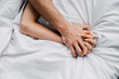 © LIGHTFIELD STUDIOS - Top view of woman holding hand of boyfriend on bed
