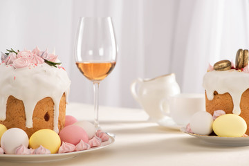 Wall Mural - delicious Easter cakes decorated with meringue near colorful eggs on plates and wine glass