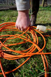 Gardener raising an extension cord. Homemade extension cord on the grass left by the gardener. Work in the home garden.
