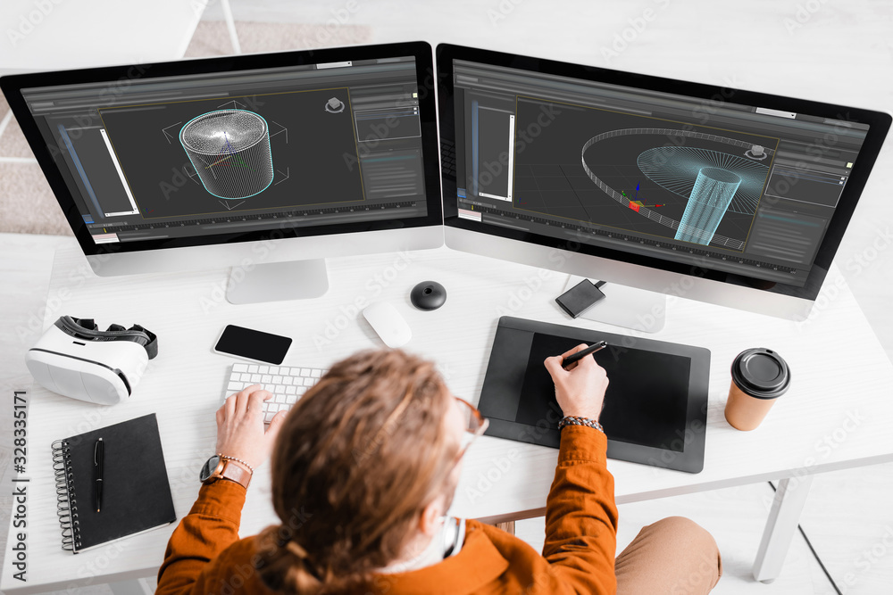 Overhead view of 3d artist using graphics tablet and computers while ...