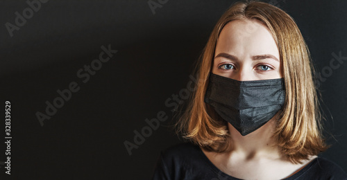 A girl with a protective black mask on her face to protect her from the coronavirus. Coronavirus pandemic,covid-2019.Chinese outbreak of coronavirus. Banner
