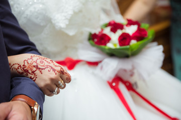 Let's get into the groom's arms. The bride holds a red bouquet in her hand. Hands and fingers are drawn to henna .