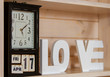 On the shelf are vintage watches that also indicate the date, month and day of the week: Friday April 17th. out of focus of the wooden letters is the word love .