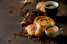 Variety Of Traditional French Puff Pastry Raisin And Chocolate Buns, Croissant With Various Cups Of Coffee Paper And Ceramic, Coffee Beans, Recycled Wooden Spoon Of Sugar Over Dark Texture Background.