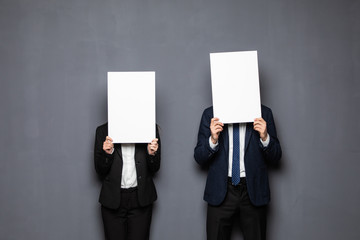 Wall Mural - Business couple holding paper over their faces on gray background