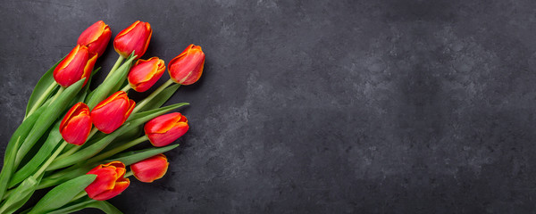 Greeting Card for Mother's or Women's Day. Bouquet of red tulips on a dark stone table. Spring background. Top view. Copy space