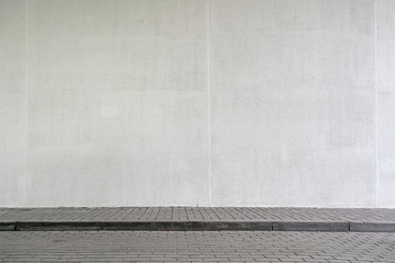 building with high white wall near empty sidewalk covered with grey stone tiles