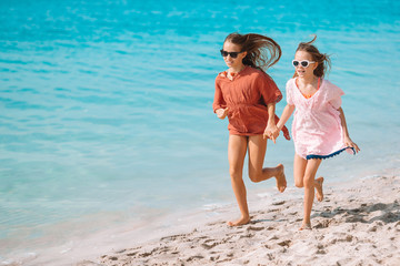 Little happy funny girls have a lot of fun at tropical beach playing together.