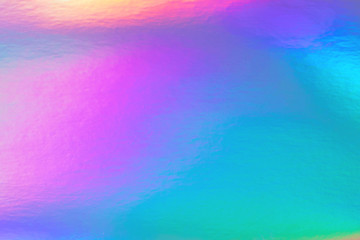 Abstract trendy rainbow holographic background in 80s style. Blurred texture in violet, pink and mint bright neon colors.