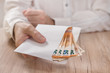 Męska dłoń trzyma białą kopertę wypełnioną banknotami waluty Euro i podaje ją ponad stołem.