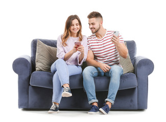 Sticker - Young couple with mobile phones sitting on sofa against white background