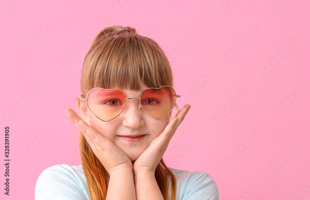 Funny little girl with sunglasses on color background