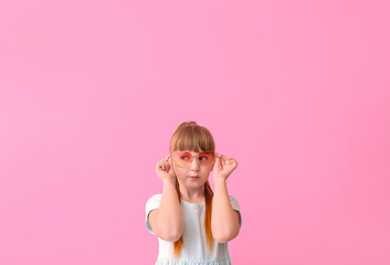 Wall Mural - Funny little girl with sunglasses on color background