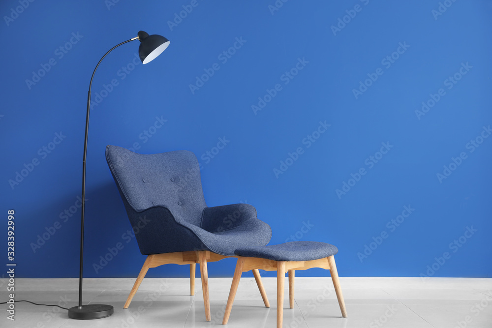 Modern armchair, stand and lamp near color wall