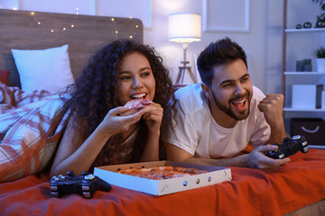 Wall Mural - Happy young couple playing video games in bedroom