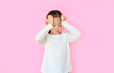 Little asian girl suffering from headache desperate and stressed because pain isolated on pink background. Kid with hands on head