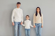 © Studio Romantic - Happy family smiling while standing against gray background.