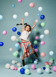 © Dmitry Lobanov - Happy asian kid girl in stylish striped maxi skirt has fun jumps dances surrounded by colorful air balloons