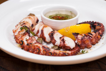 grilled squid rings on a wooden board with sauce