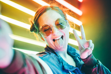 portrait of modern young woman making selfie at the neon light.