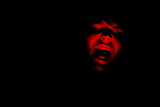 Fototapeta Tęcza - Maniac face silhouette illuminated by torch on black background. Dark background. Horror background. Black background. Halloween horror concept.