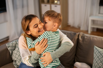 family, love and people concept - happy smiling mother and little son hugging and kissing at home in