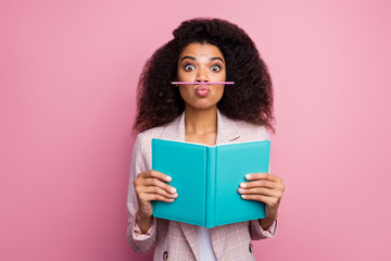 Poster - Photo of funny foolish dark skin student lady hold journal book not reading playing pen make fake mustache wear checkered blazer isolated pastel pink color background